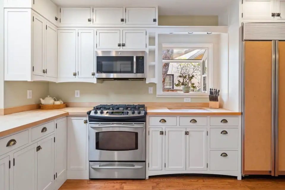 Bright chef-ready kitchen with gas range, shaker cabinets, and window light