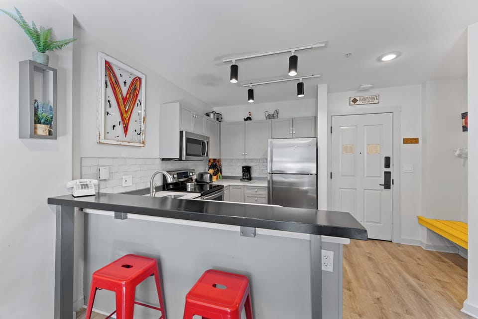 Your bright kitchen features sleek counters, modern appliances, and a breakfast bar where you can sip morning coffee on vibrant red stools.