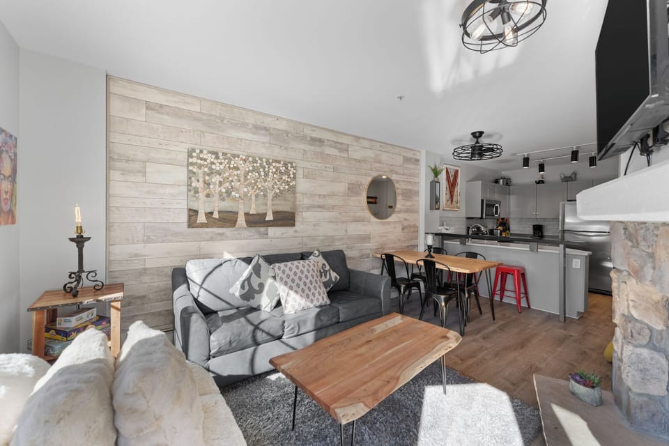Relax in your stylish open-concept space featuring rustic wood accents, modern furnishings, and a fully equipped kitchen perfect for home-cooked meals.