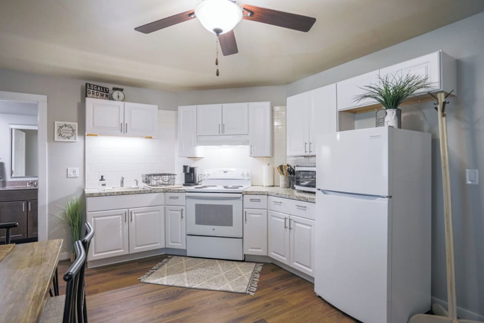 A modern kitchen equipped with high-end appliances and ample lighting. It has a coffee maker, oven, stove top, utensils, and all it takes to fix a delicious meal.