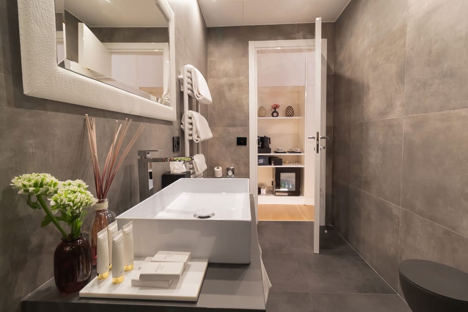 Deluxe Suite, City View | Bathroom | Rainfall showerhead, designer toiletries, hair dryer, slippers