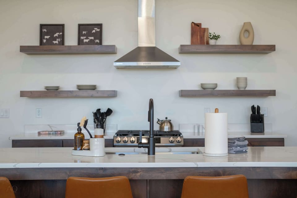 Sleek designer kitchen with quartz countertops, statement hood & curated open shelving.