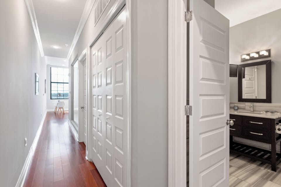 Indoor hallway with modern white doors and hardwood flooring leading to bright living area.