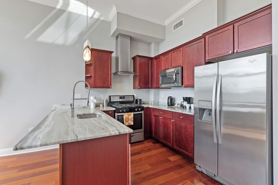 Full kitchen with cherry cabinets, gas range, and modern appliances providing all the tools for delicious meals.