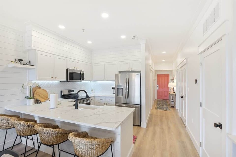 - Cook with ease in this modern kitchen featuring stainless steel appliances and white cabinetry - Marble look island with seating for four is perfect for casual bites or morning coffee - Open layout connects smoothly to the entry and main living spa
