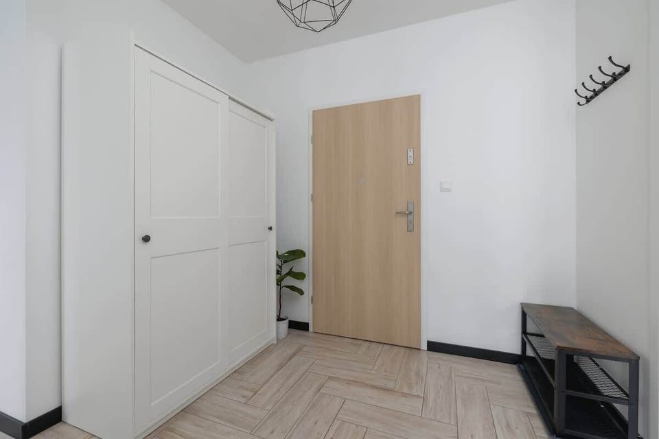 A bedroom entrance with a large wardrobe and full-length mirror. Neutral tones create a calm atmosphere.