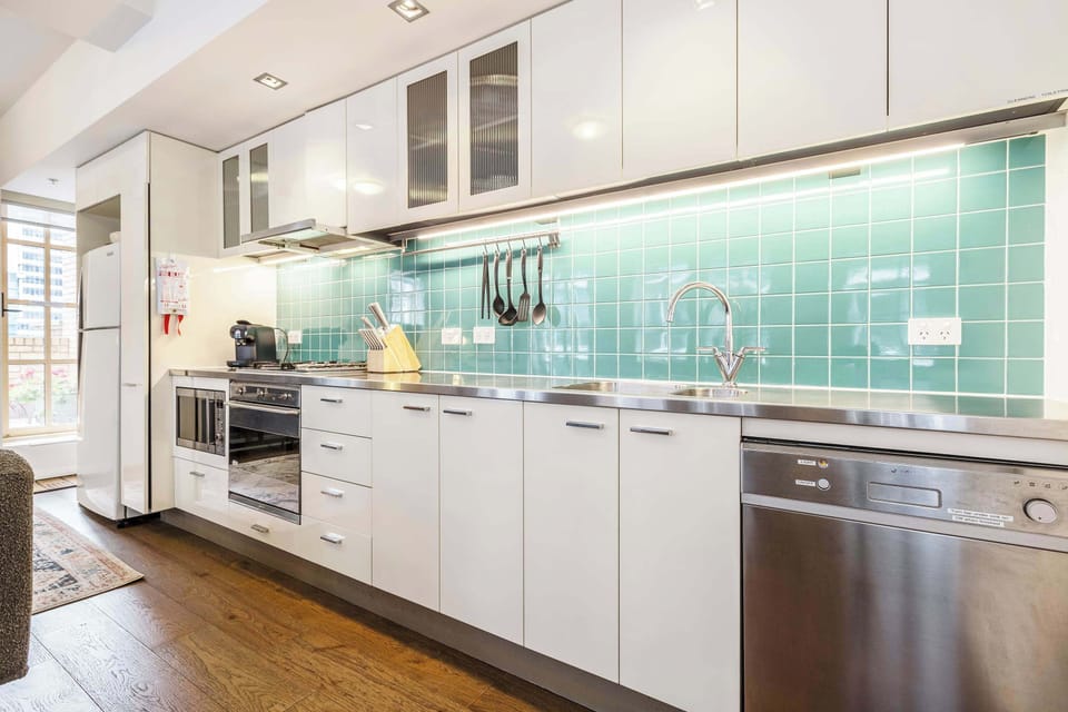 Kitchen at Tribeca: Modern kitchen with stainless steel appliances and sleek green tile backsplash