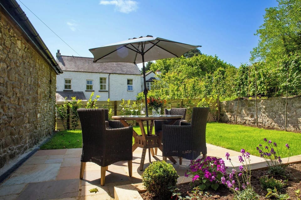 Secure garden with lawn and patio area with table, chairs and parasol