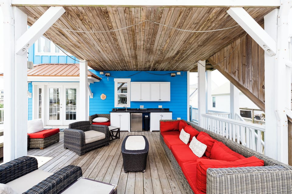 Relax under your private covered deck with bright outdoor kitchen and vibrant wicker seating perfect for entertaining.