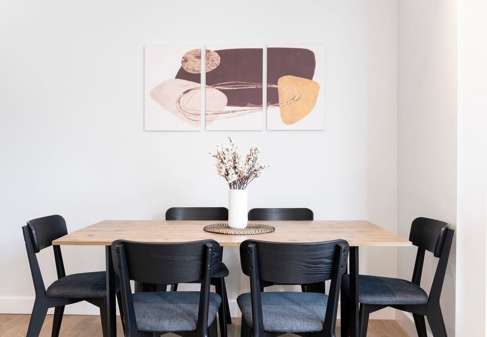 Open-plan living area and kitchen with a sofa bed, TV, dining table, and six chairs.