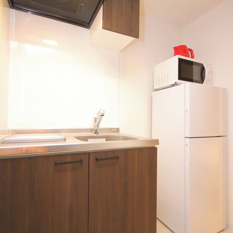 The kitchenette is equipped with a large refrigerator with freezer, electric kettle, and microwave.