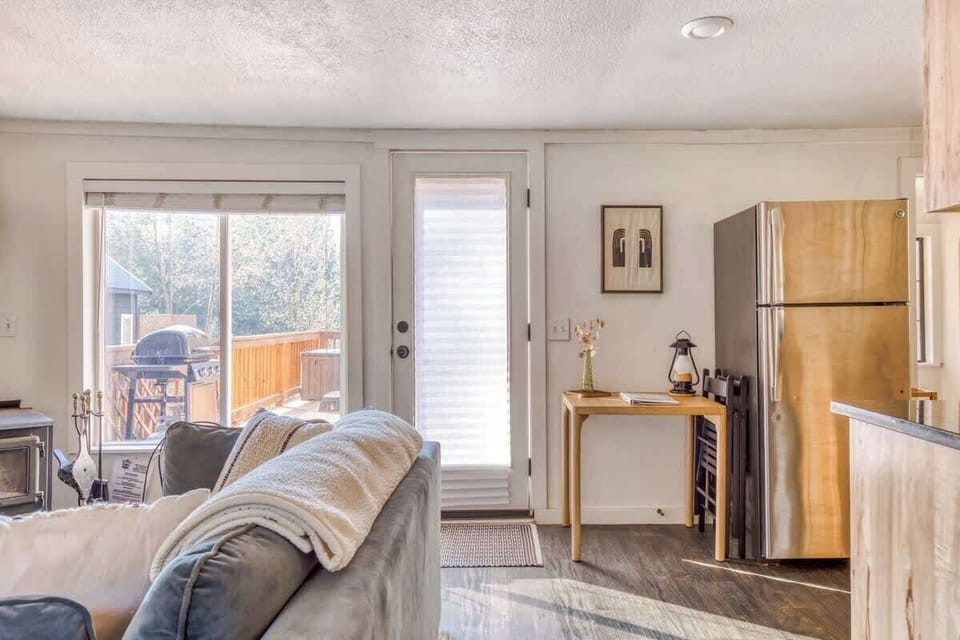 That soft light pouring in over the deck and the little writing table make the space feel calm and lived-in. Everything’s practical but still has style—cozy without trying too hard.