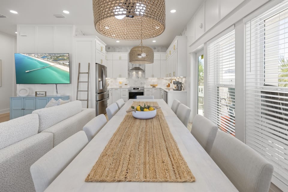 Gather around this bright dining table for memorable meals with natural light streaming through coastal windows and ocean views.