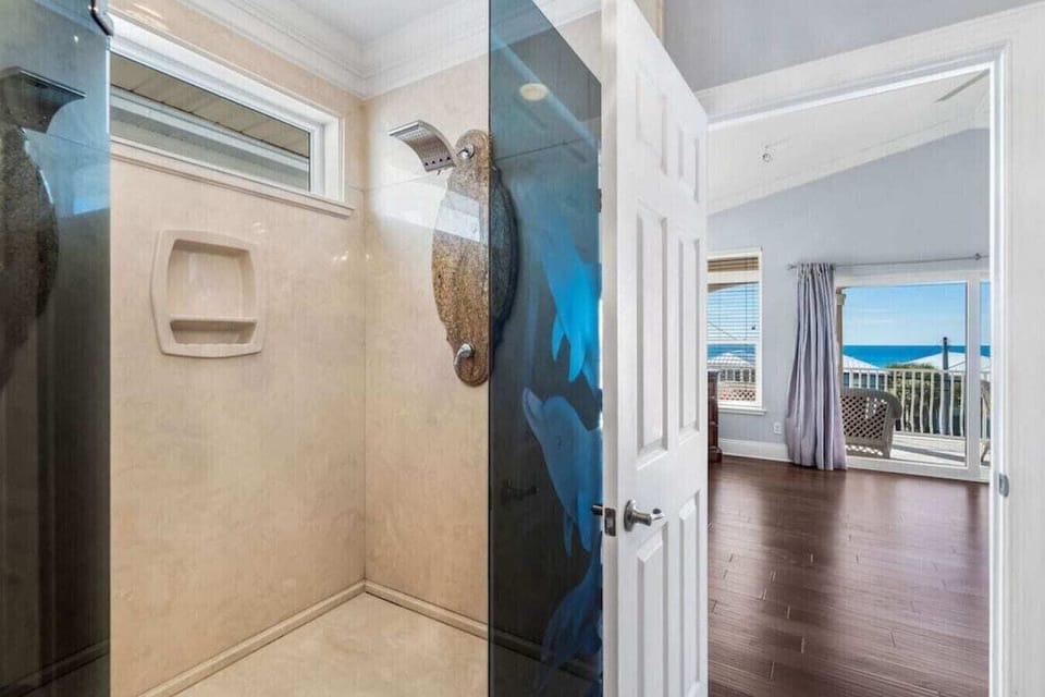 Your private shower awaits with spa-like luxury and stunning ocean views beyond.
