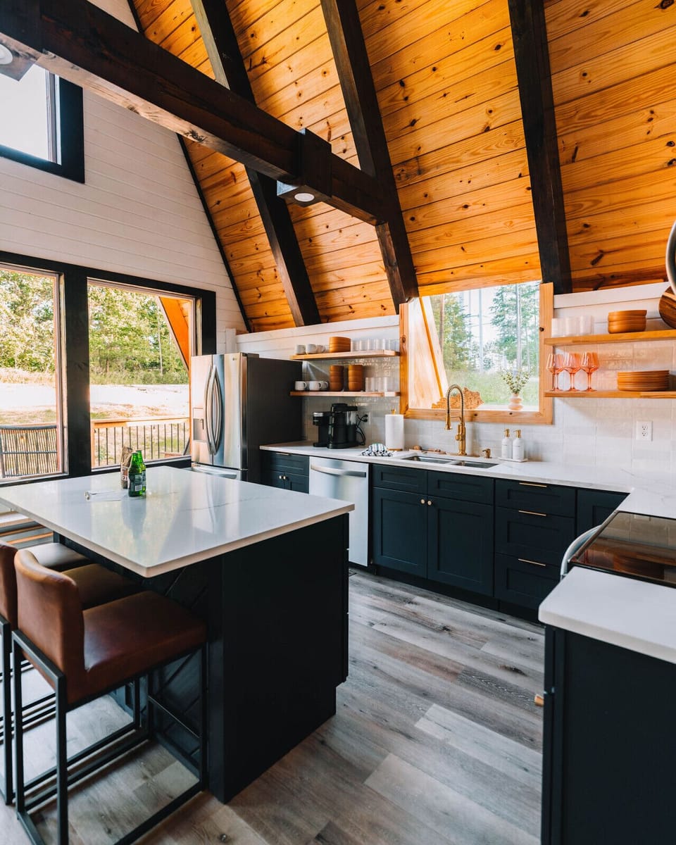 A-frame architecture meets modern function — this kitchen is where golden-hour light, open shelving, and quartz countertops over three bar stools make every meal feel like a moment.