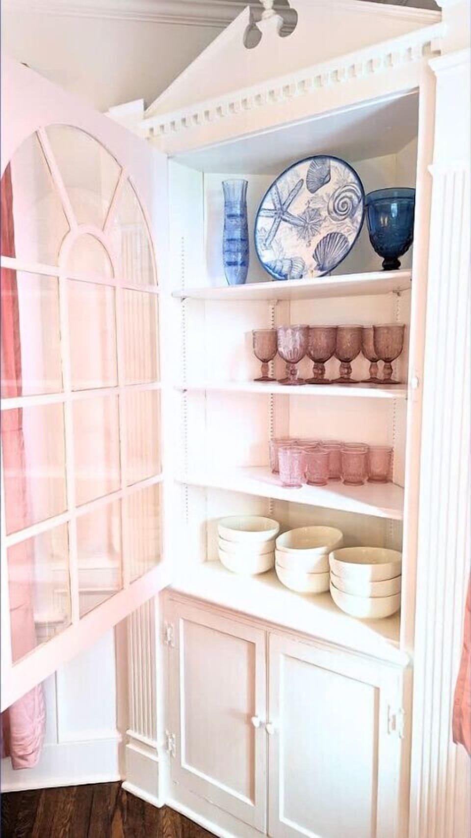 Antique style glassware, serving dishes, and salad bowls line the shelves of this original built-in hutch.