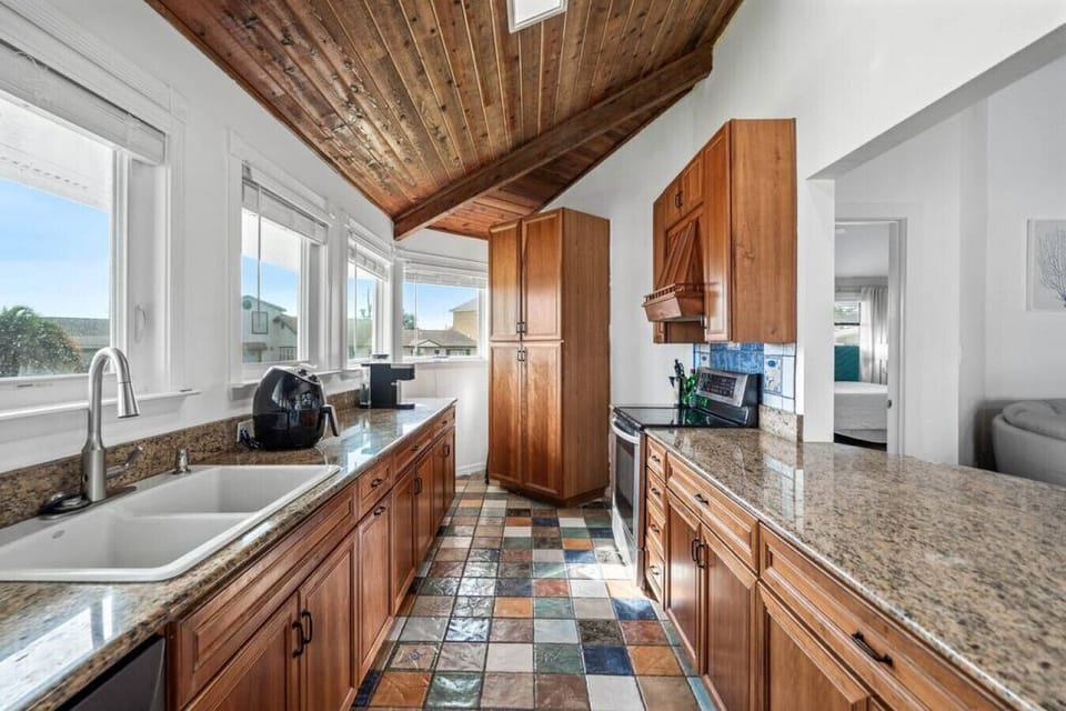 Your gourmet kitchen awaits with warm wood cabinets, granite counters, and charming exposed beams creating a perfect cooking sanctuary.