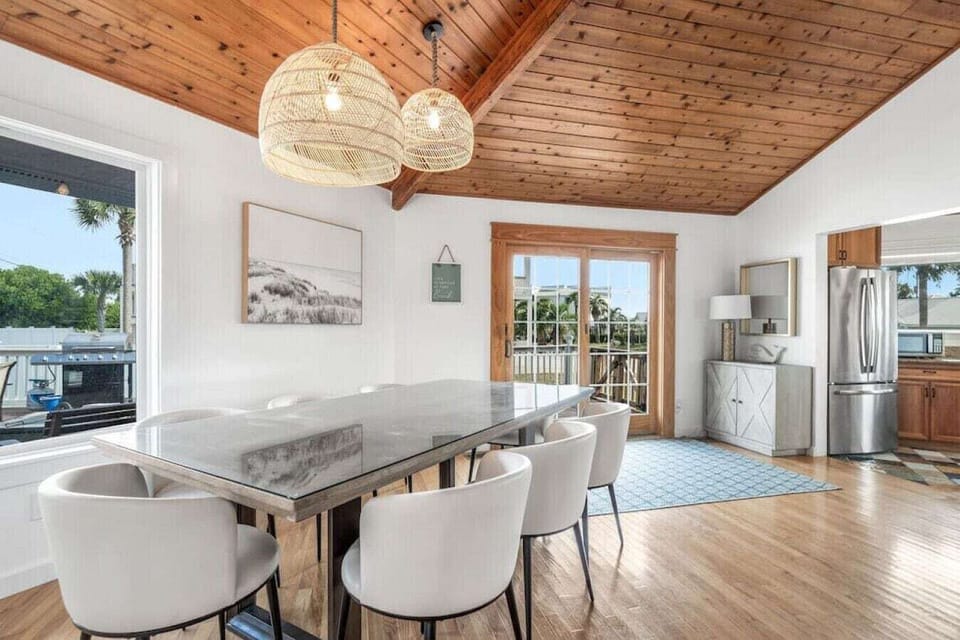 Gather around this stunning dining table under natural woven pendants, where warm wood beams create an inviting atmosphere for your memorable meals.