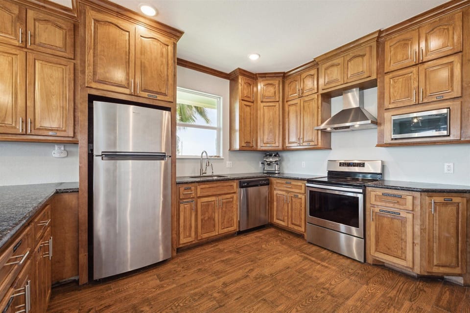 The kitchen is equipped with a full suite of stainless steel appliances, including a Whirlpool convection oven, electric stove top, refrigerator, and LG microwave.