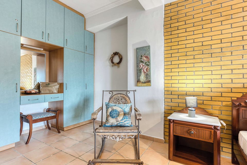 Natural light bathes this tranquil corner, highlighting the unique blend of textures and colors. The rustic rocking chair beckons you to unwind with a good book, while the modern cabinetry provides ample storage space for your belongings.