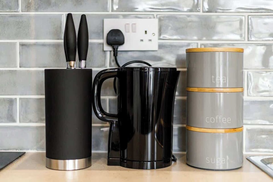 - Modern kitchen counter with kettle knife set and storage jars  
- Subway tile backsplash complements sleek black and grey design  
- Airbnb kitchen detail ready for cooking tea and easy guest use  
