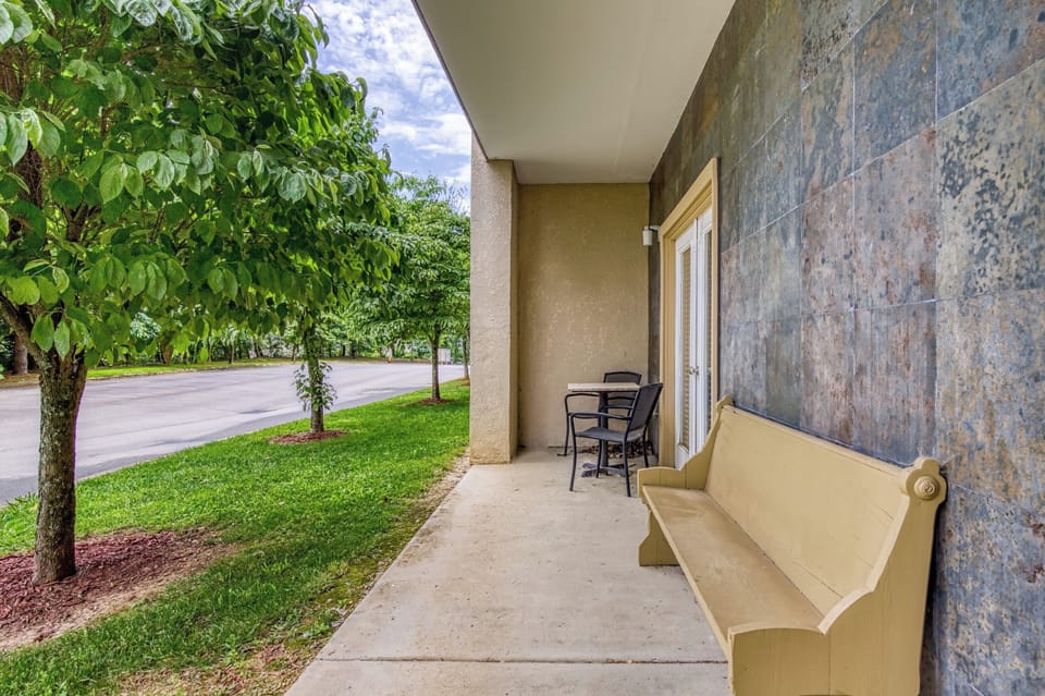 Outdoor Patio, Trees, Grass, Concrete, Table, 2 Chairs, Bench, Tile, Covered.
