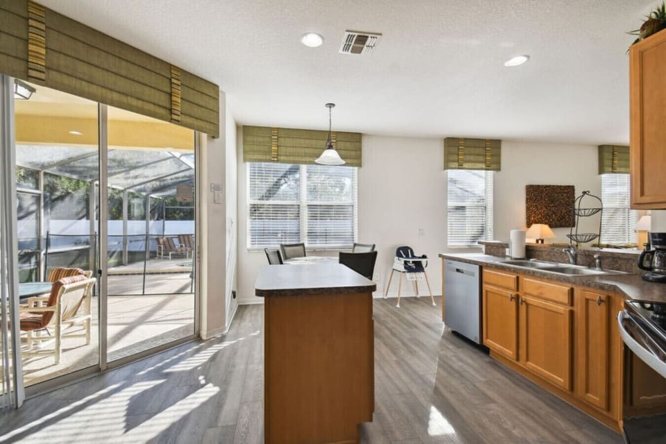 Bright kitchen with island seating and poolside views.
