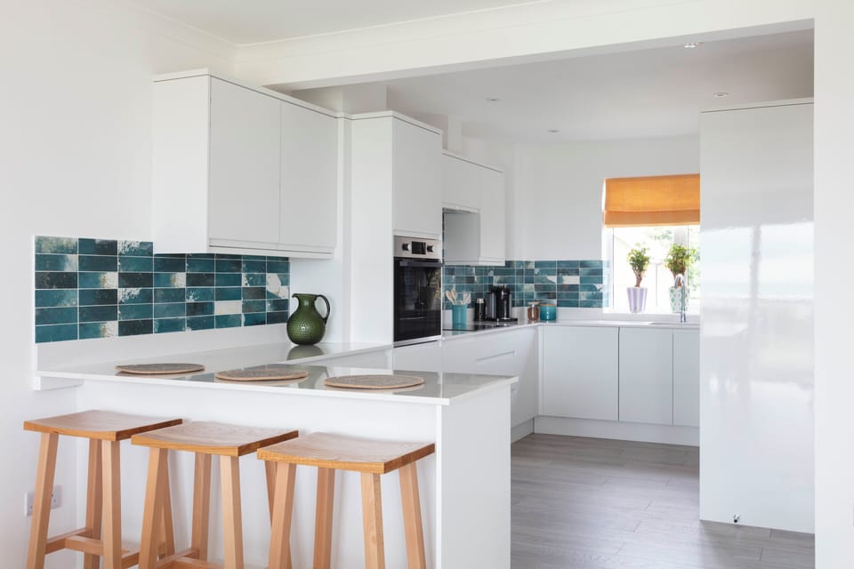 Kitchen area with blue and white tiling, Breakfast bar and cupboard storage 