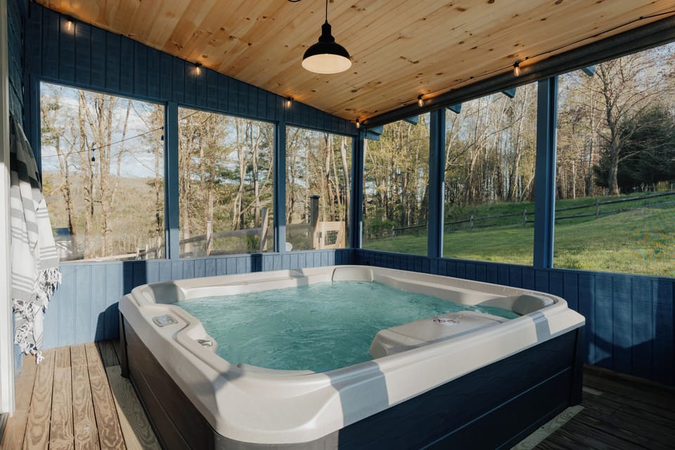 Indulge in the luxury of a unique hot tub experience at Kohler Cabin, nestled within a serene screened-in porch. Here, you can immerse yourself in warmth and relaxation regardless of the weather, with the gentle patter of rain adding to the ambiance