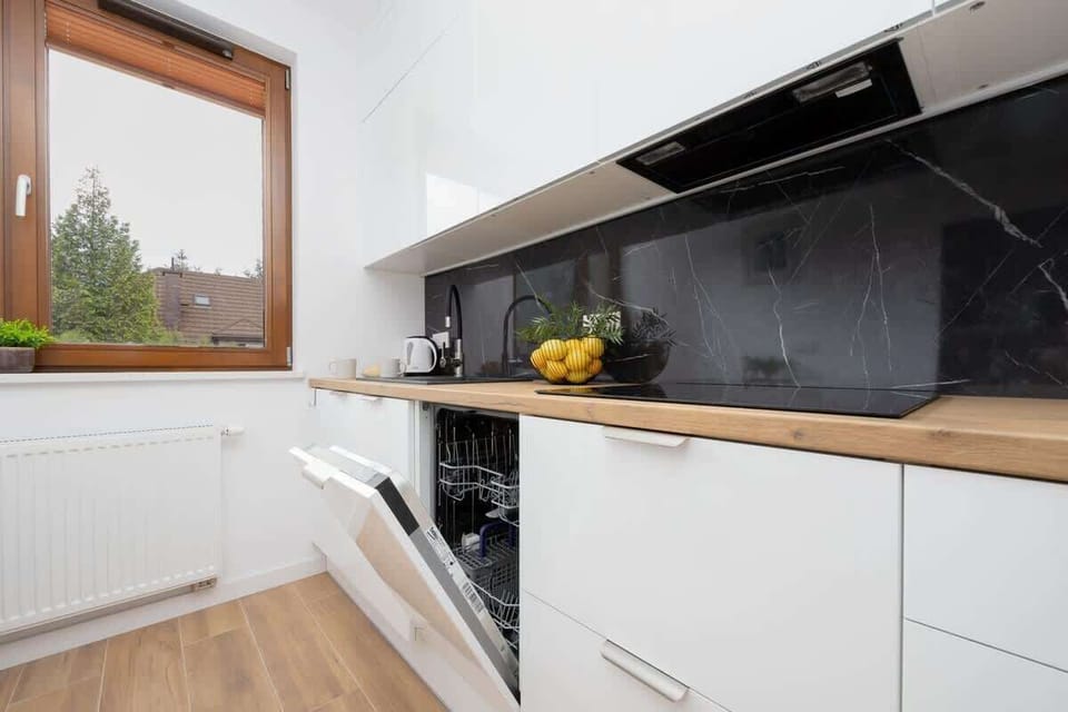 Bright kitchen with white cabinets and dishwasher.