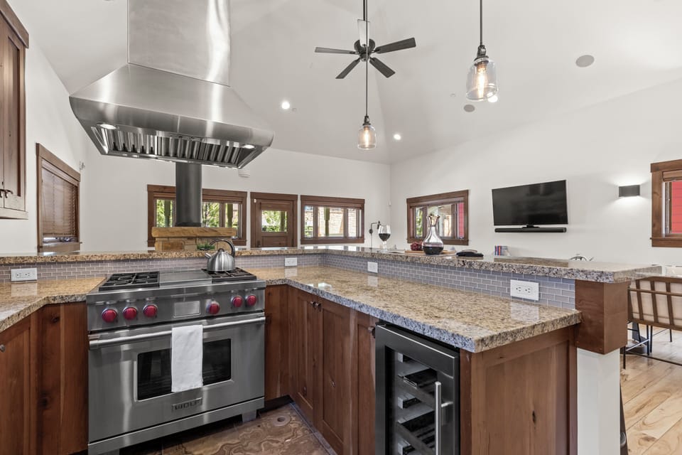 Town Lift Chalet's kitchen with breakfast bar, stainless steel Wolf range, stainless hood vent, and wine fridge.