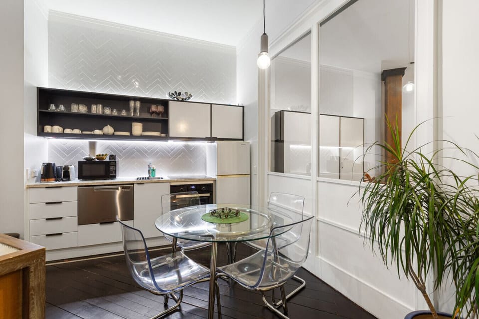 Modern kitchen with sleek finishes and a glass dining table, ideal for relaxed indoor dining.
