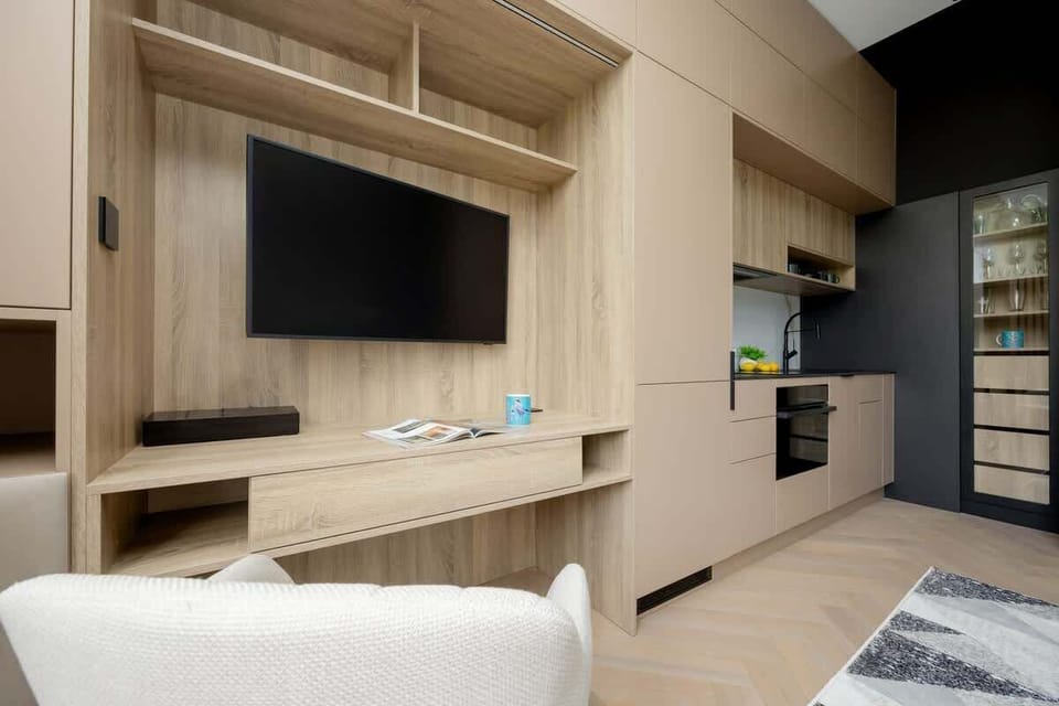 Compact living room with stylish furniture – Includes armchair, coffee table, and Smart TV for streaming.

