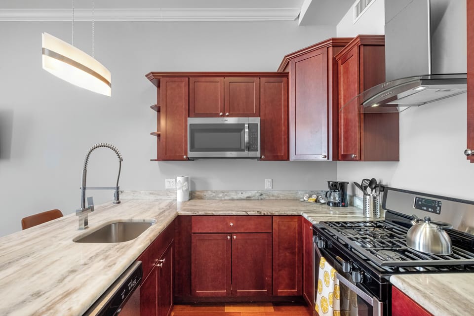 Fully-equipped kitchen with cherry wood cabinets, stainless appliances, and granite counters ideal for preparing home-cooked meals.