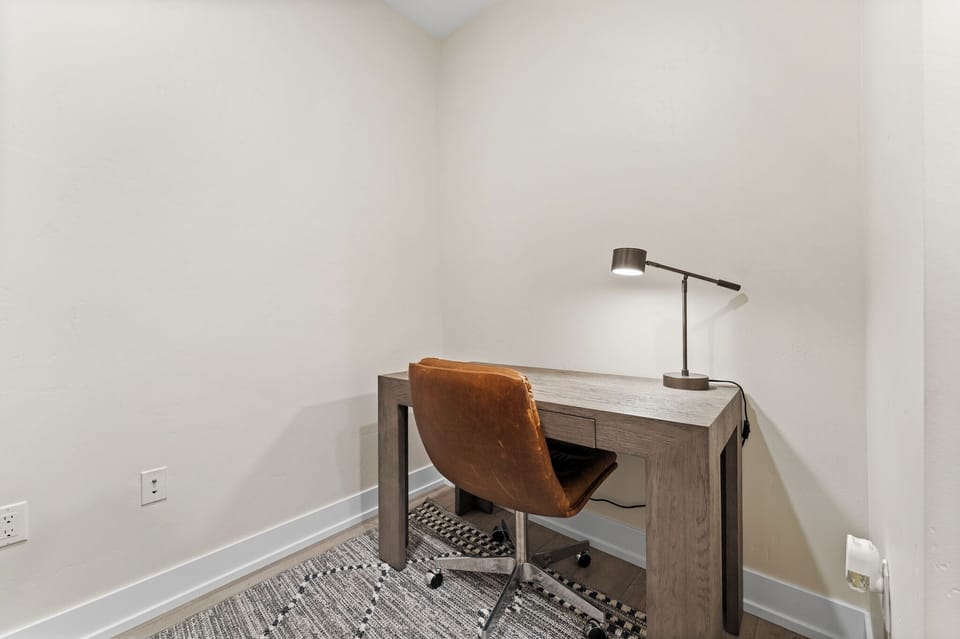Your private workspace awaits with a sleek desk, comfortable leather chair, and focused task lighting for productive mornings or evening planning.