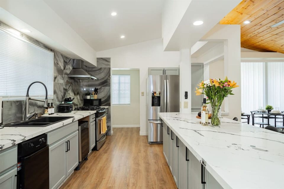 Fully Equipped Chef`s Kitchen: Channel your inner chef in this spacious, light-filled kitchen featuring marble-style quartz countertops, a large kitchen island, stainless steel refrigerator, gas stove, dishwasher, and modern kitchen faucet.