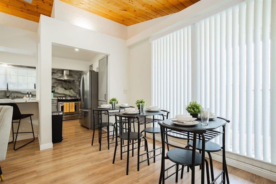 Open Kitchen & Dining Space: Transition effortlessly from cooking to eating in this open-concept layout, highlighting high-top dining seating, a kitchen pass-through counter bar, stainless steel appliances, and abundant natural light.