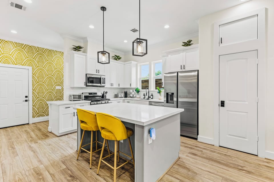Bright designer kitchen with large island, bold accents, and seating for two