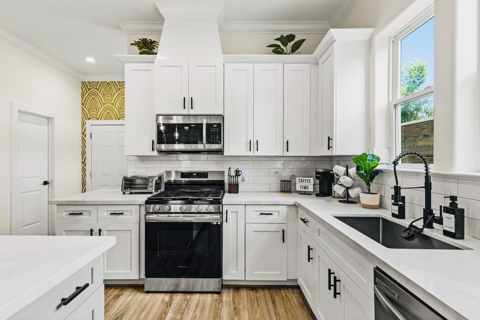 Bright modern kitchen with gas range, farmhouse sink, and abundant natural light