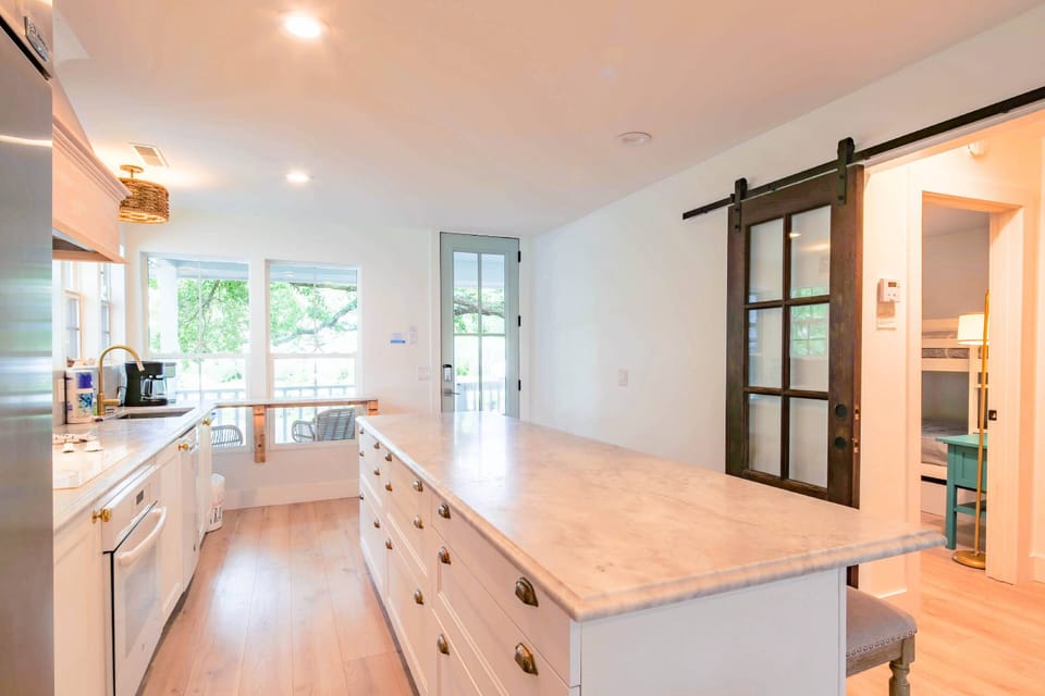 When you enter the front door, you will find the home's kitchen with a central island and white cabinets.