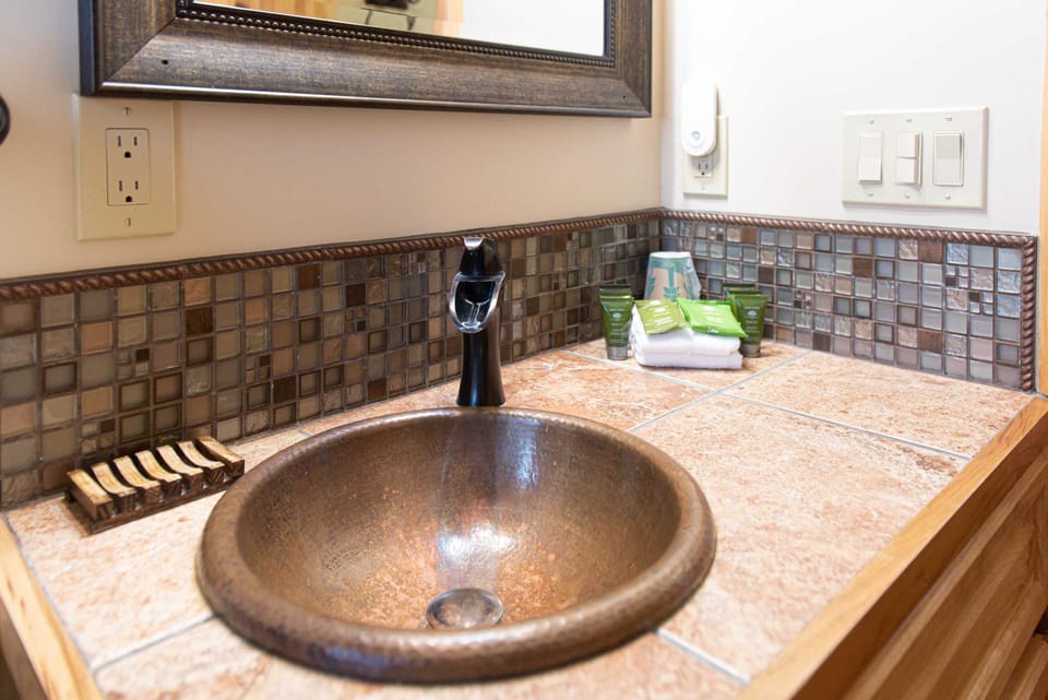 Penny copper sink, tiled countertop, surrounded with backsplash and luxerious hotel soaps.