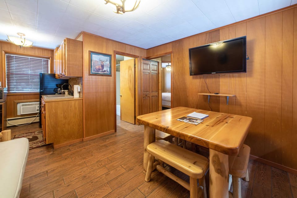 Sitting area with a futon, wood dining table, and a large tv.