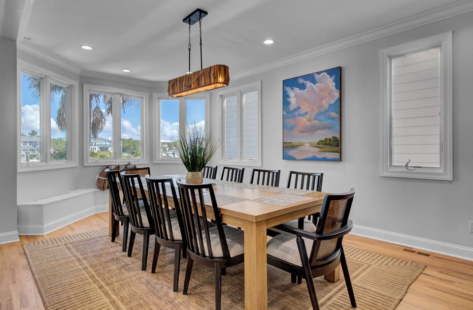 Gather your group around this elegant dining table where natural light streams through panoramic windows, creating the perfect setting for memorable meals together.