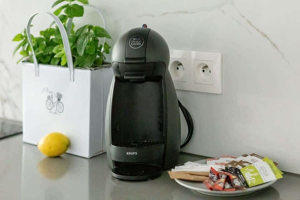 A coffee station with a capsule coffee machine, cups, and small kitchen accessories.