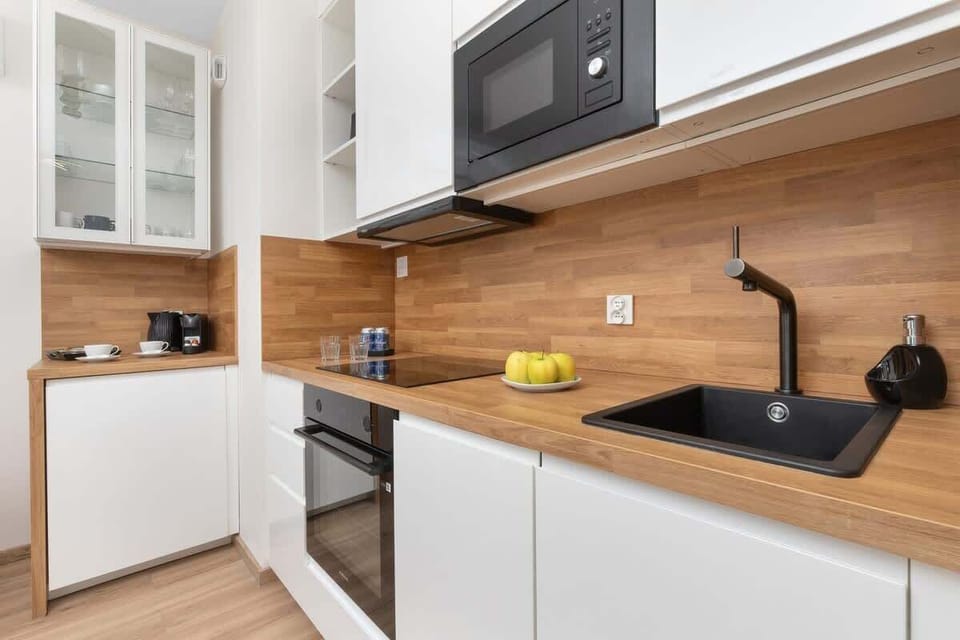 A compact kitchen with sleek white cabinets and integrated appliances.

