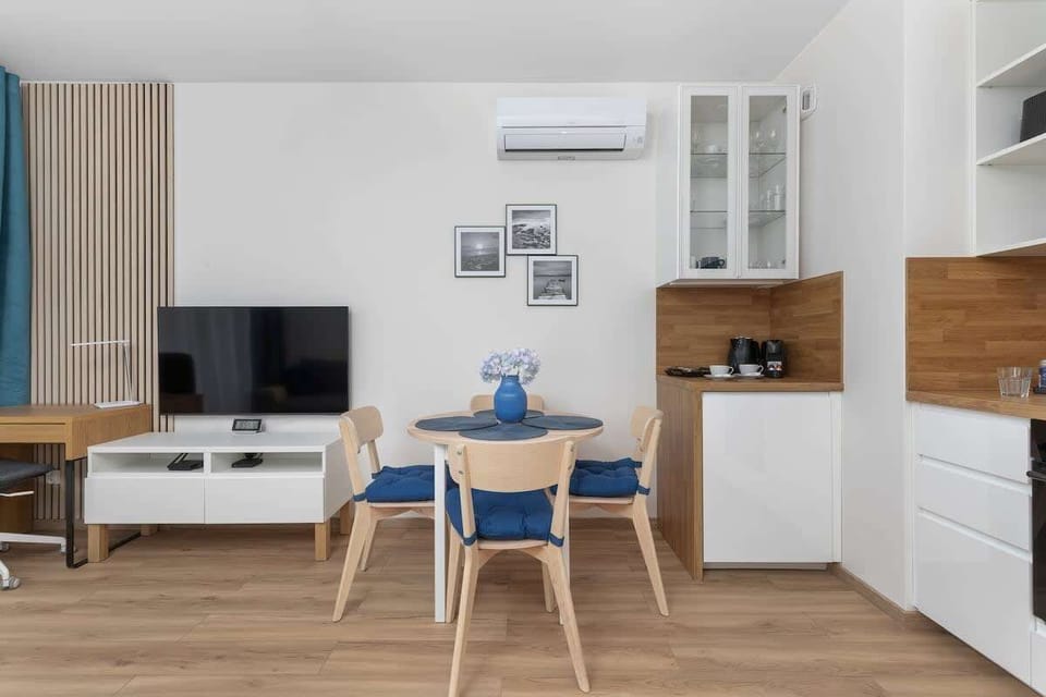 A combined living and dining space with a TV unit and light wooden furniture.

