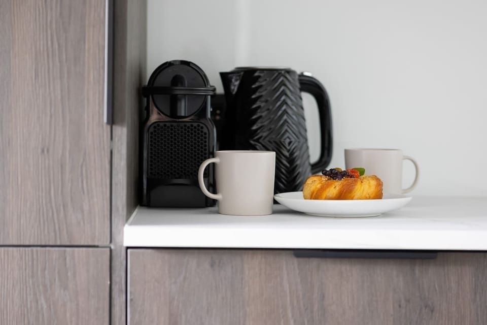 A coffee station built into the kitchen cabinetry with a kettle, mugs, and fruit on display.

