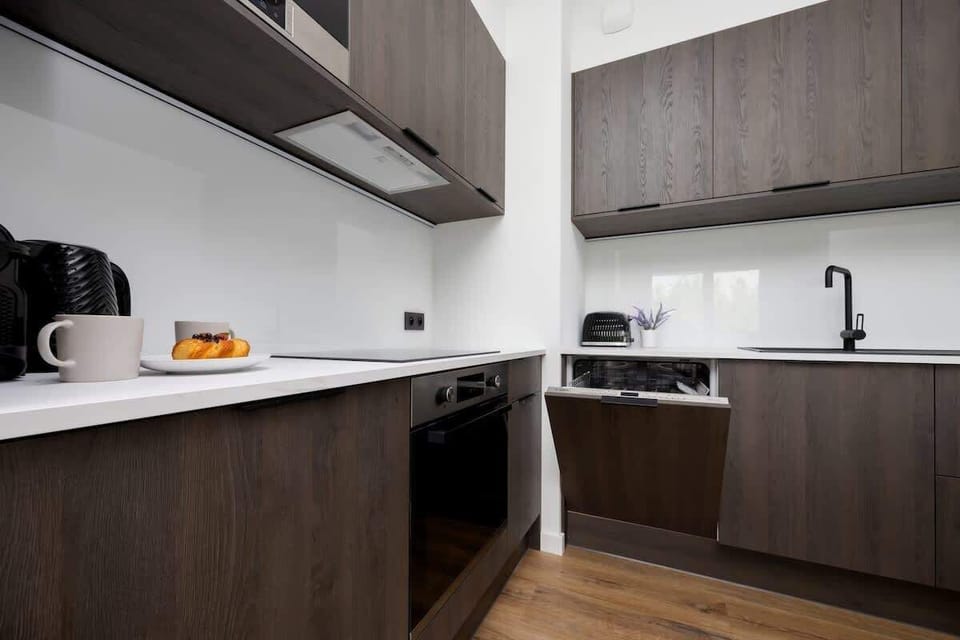A clean kitchen setup with modern fittings, under-cabinet lighting, and dark cabinets.

