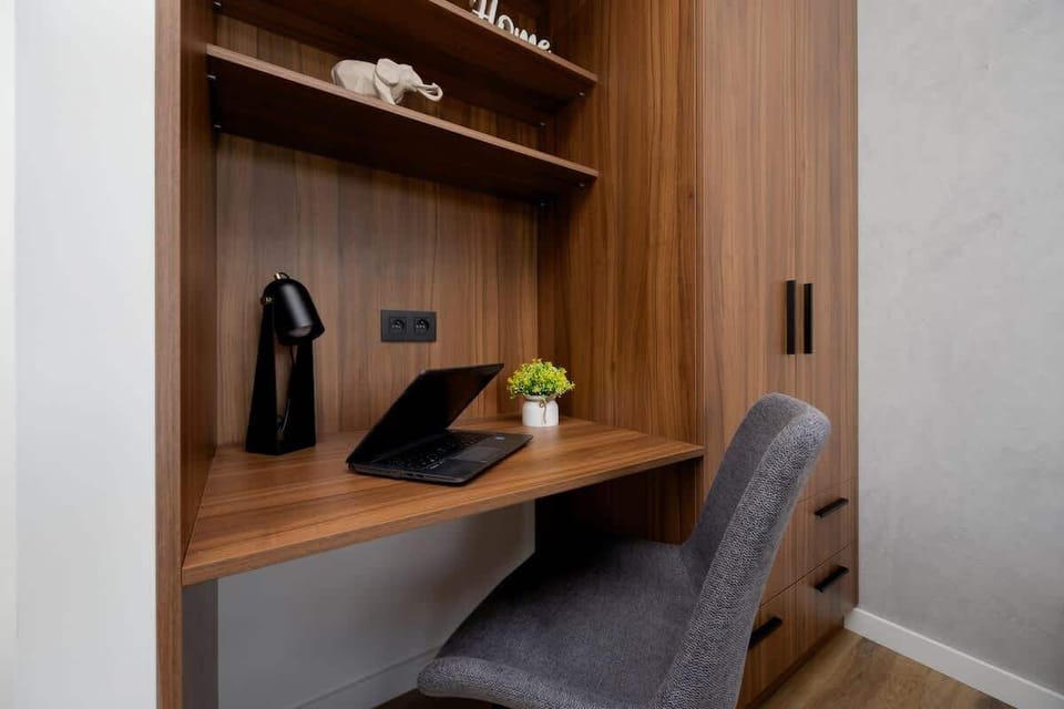 A functional workspace in the bedroom, including a built-in desk, shelves, and a reading chair.

