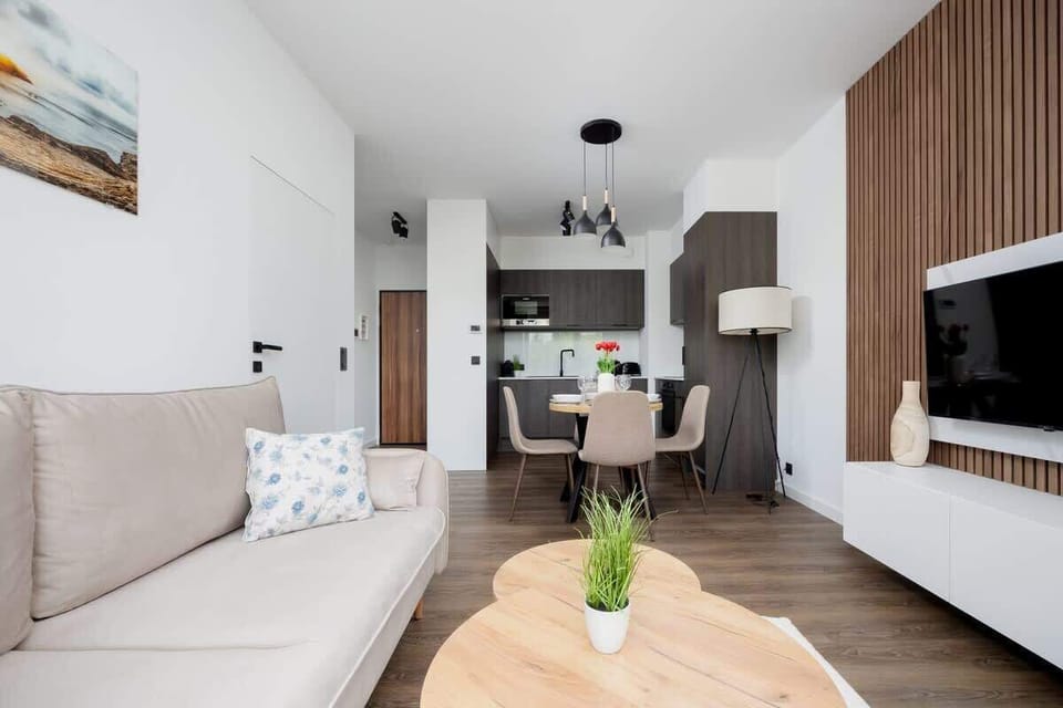 Sofa, wyjście na balkon, telewizor, stolik kawowy, obraz, dywan, zasłony, regał, szafka pod telewizorem, stół, 4 krzesła, aneks kuchenny
